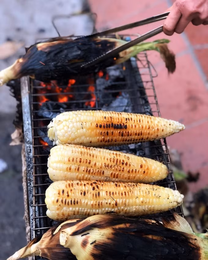 Ngô khoai nướngNhư các món ăn vặt khác, ngô nướng ở Hà Nội cũng không cầu kỳ, chẳng cần mỡ hành, không cần bơ. Bởi nó ngon ở chính những bắp ngô đã được chọn kỹ và phải là ngô bánh tẻ vừa tới, không quá già để bị sượng cứng và cũng không quá non để bị teo hạt. Khoai nướng là thức quà bên ngoài xấu xí nhưng bên trong thơm ngon, đặc biệt hấp dẫn khi ăn trời lạnh. Riêng ngô, khoai nướng chẳng phải cất công đi tìm, bạn chỉ việc lượn phố những ngày mùa đông sẽ bắt gặp ngay vô số các bếp than hồng bên vỉa hè. Giá mỗi bắp ngô hoặc củ khoai khoảng 10.000 - 15.000 đồng. Ảnh: Huyền Dương
