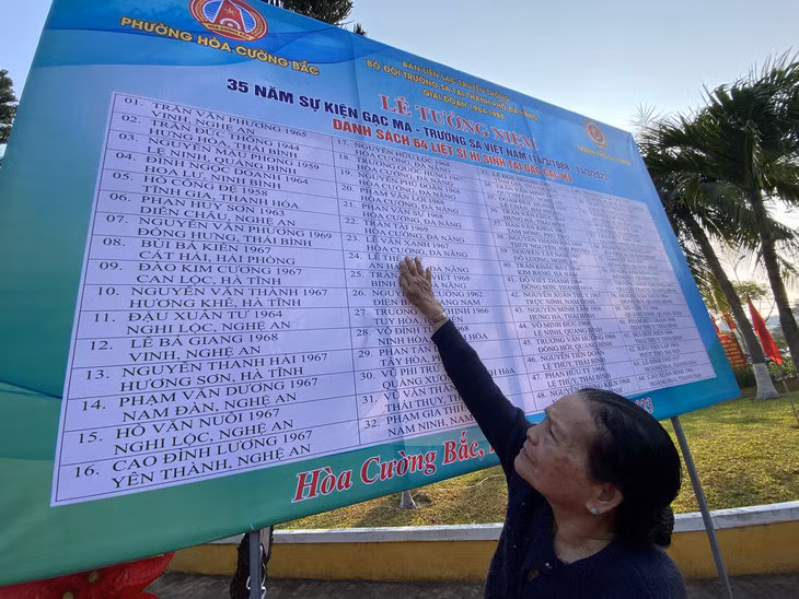 Bà Trần Thị Huệ - mẹ liệt sĩ Lê Thế - lần tìm tên con trong bảng ghi danh 64 liệt sĩ hy sinh tại Gạc Ma - Ảnh: B.D.