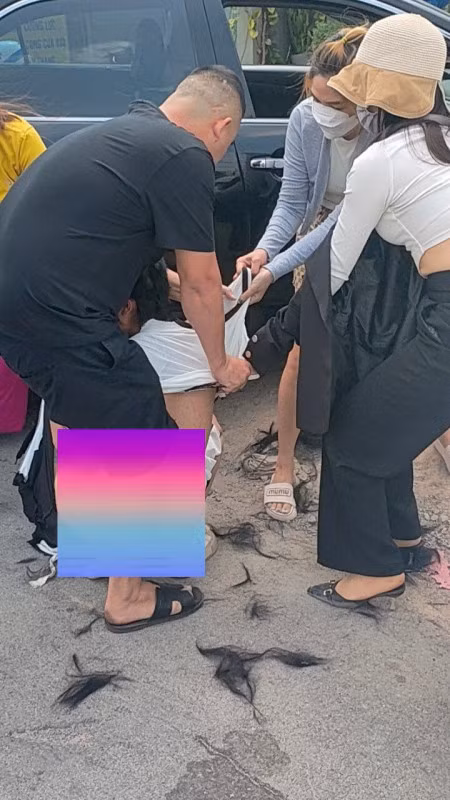 Người phụ nữ bị cắt tóc, lột đồ dù có người đàn ông áo đen bảo vệ.