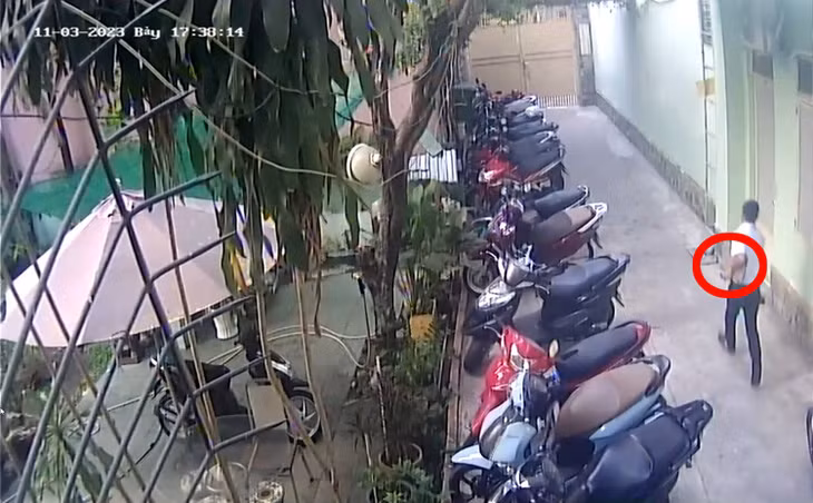 Người đàn ông tay ôm máy tính xách tay chạy ra ngoài cổng. Ảnh cắt từ clip