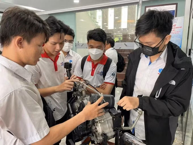 Trần Lê Phước (trái) giới thiệu hệ thống chống ngập tích hợp vào xe máy với các sinh viên cùng trường. Ảnh: Hà An