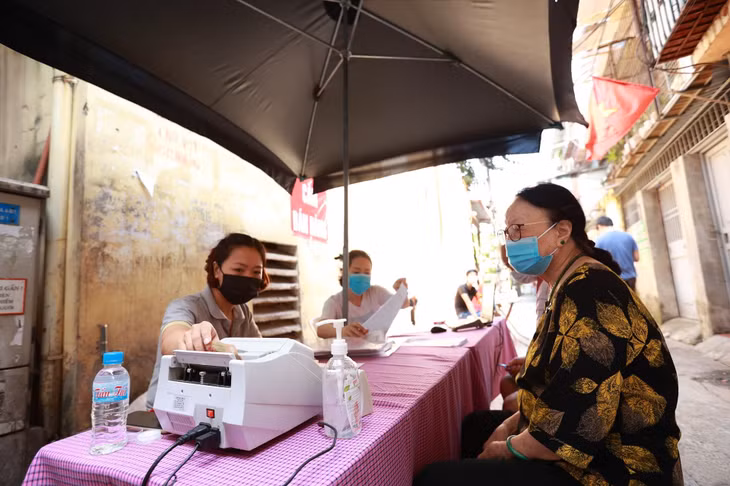 Cán bộ bưu điện Hà Nội chi trả lương hưu, trợ cấp BHXH cho người dân. Ảnh: Hải Nguyễn