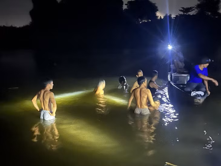 Người dân rọi đèn pin và mò mẫm tìm kiếm ba ông cháu tắm sông đuối nước - Ảnh: Q.V.