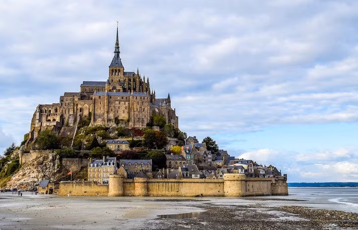 Được biết đến là “kỳ quan của thế giới phương Tây", lịch sử của Mont Saint-Michel bắt đầu từ năm 709 khi tu viện được xây dựng để tôn thờ Thánh Michael, Tổng lãnh thiên thần. Nơi này đã trở thành một địa điểm linh thiêng và tiếp tục phát triển suốt thế kỷ 11-16. Ảnh: Mont Saint Michel Tickets.