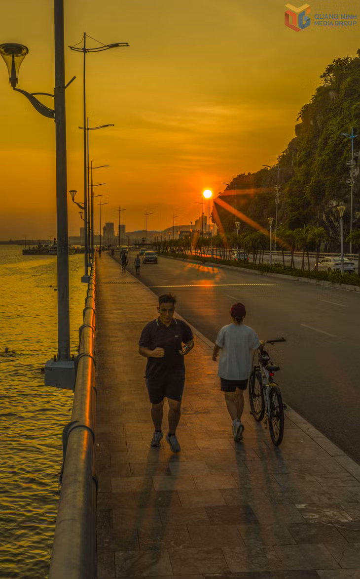 Người dân rèn luyện thể thao dọc tuyến đường ven biển trong ánh hoàng hôn buông xuống rực rỡ.