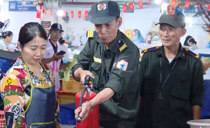 Lực lượng PCCC tại chỗ chợ Cái Dăm hướng dẫn tiểu thương sử dụng bình chữa cháy.