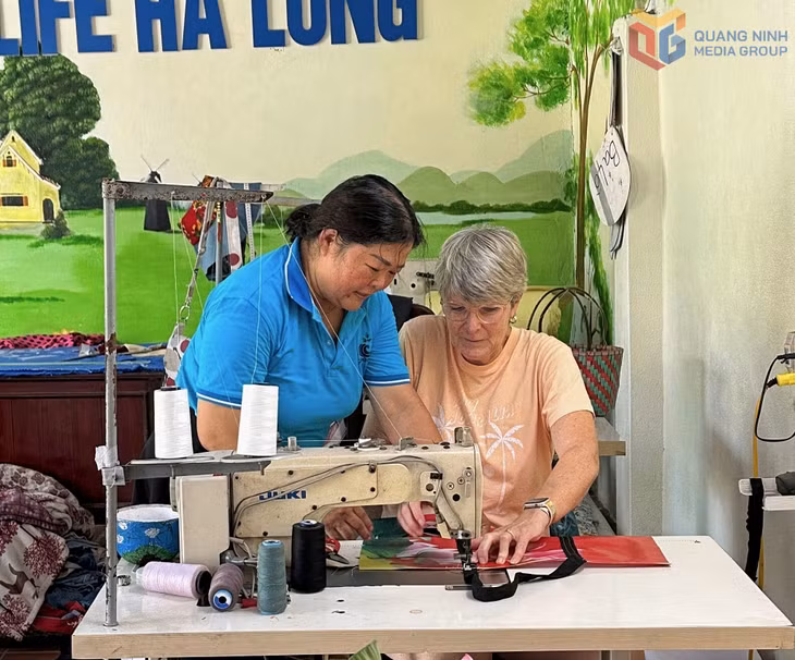 Chị Trần Thị Hương, Giám đốc HTX Green Life Hạ Long hướng dẫn du khách nước ngoài trải nghiệm may túi từ vật liệu tái chế.