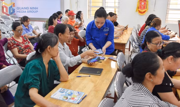 Đoàn viên thanh niên phường Vàng Danh hướng dẫn người dân tham gia lớp tập huấn kỹ năng số. Ảnh: Hoàng Giang