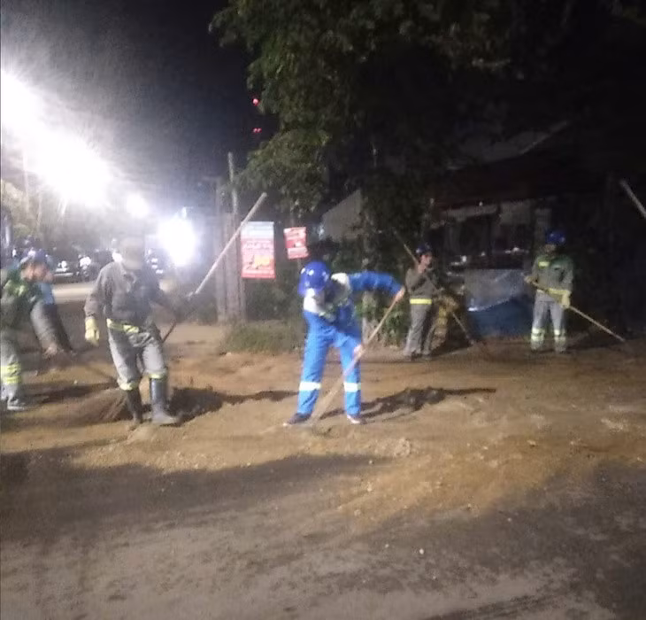 Công nhân dọn dẹp nhớt đổ ra đường bằng cách đổ rất nhiều cát để thấm số nhớt này - Ảnh: QUANG QUANG