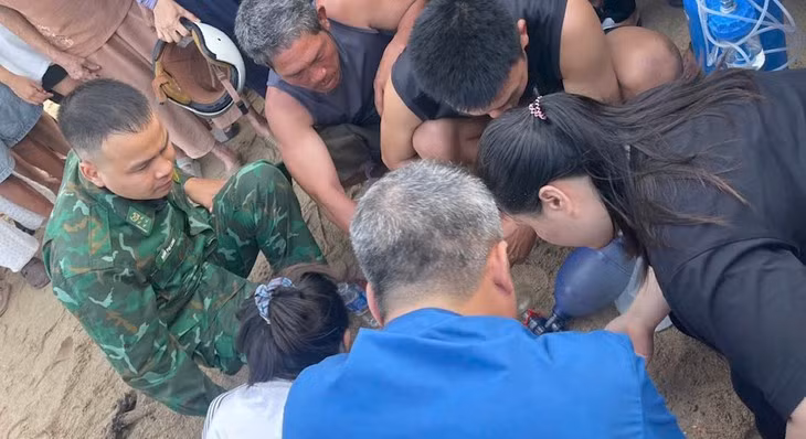 Quân y biên phòng, y tế xã đang sơ cứu khẩn cấp để cứu cháu bé bị sóng cuốn ra biển - Ảnh: T.G