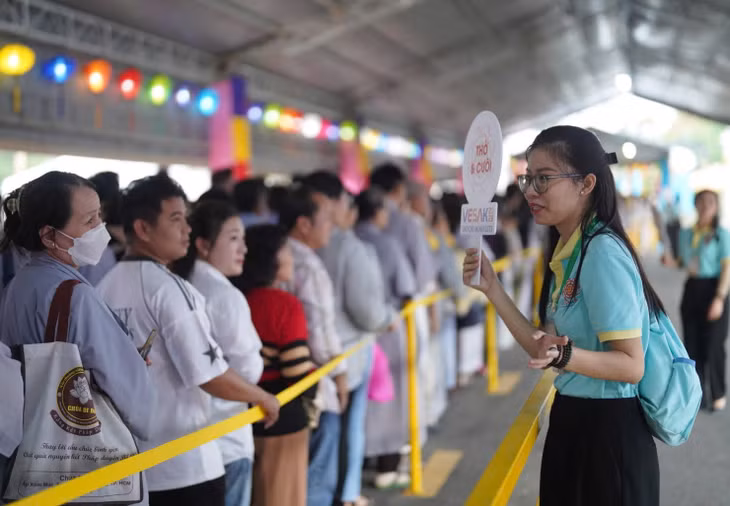 Các tình nguyện viên hướng dẫn người dân xếp hàng trước Học viện.