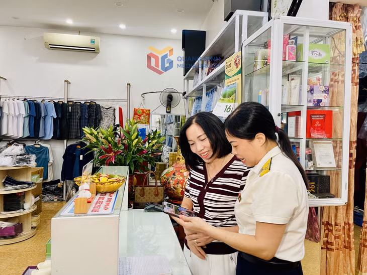 Cán bộ Đội thuế TP Đông Triều hướng dẫn các hộ kinh doanh triển khai hoá đơn khởi tạo từ máy tính tiền.