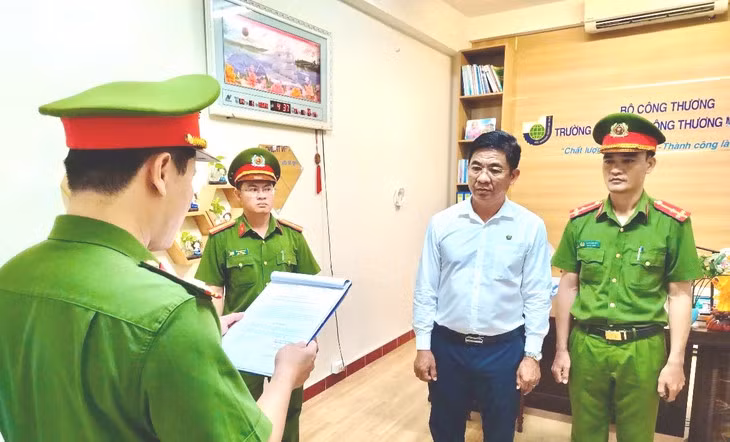 Ông Trần Kim Quyên, hiệu trưởng Trường cao đẳng Công thương miền Trung, nghe cơ quan điều tra tống đạt quyết định khởi tố bị can, lệnh bắt bị can để tạm giam - Ảnh: Công an cung cấp