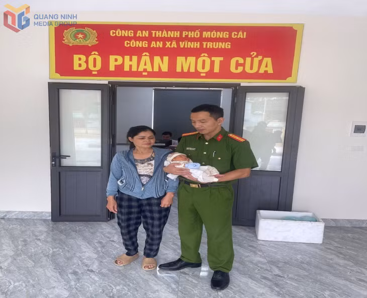 Cháu bé trong vòng tay của Thiếu tá Hoàng Minh Hiếu, cán bộ Công an xã Vĩnh Trung.
