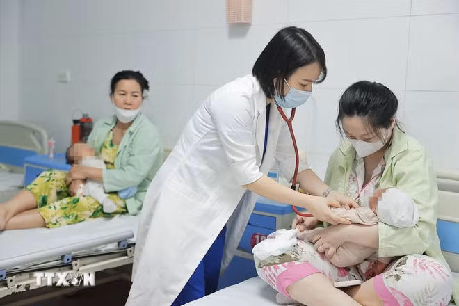 Bác sỹ khám cho bệnh nhi mắc COVID-19 đang điều trị bệnh viện Thanh Nhàn (Hà Nội). (Ảnh: Minh Quyết/TTXVN)