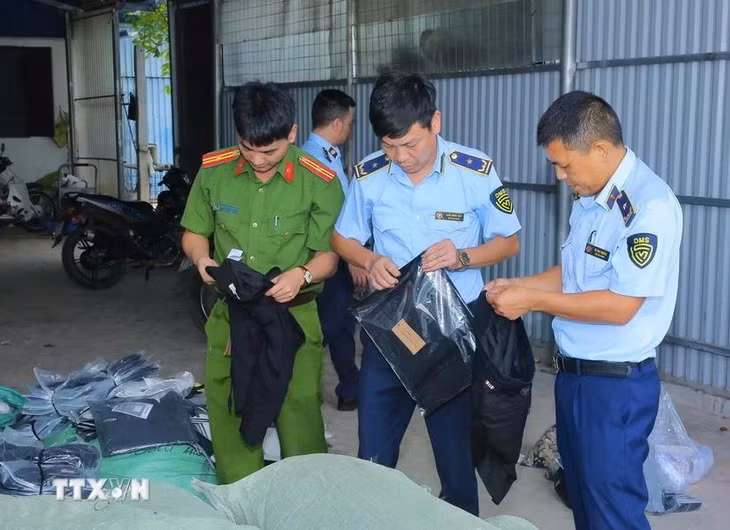 Lực lượng chức năng kiểm tra các sản phẩm may mặc giả mạo các nhãn hàng lớn. (Ảnh: Đức Phương/TTXVN)