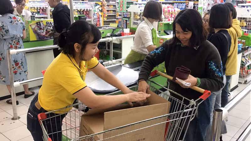 Nhân viên siêu thị Big C giúp khách hàng đóng gói đồ vào thùng các-tong. 