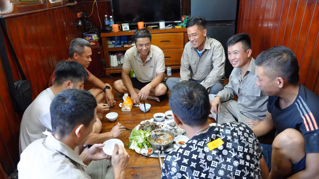 Sau những ca làm việc vất vả trên biển, các thuyền viên lại quây quần bên mâm cơm trên tàu, chia sẻ niềm vui và tình đồng đội thân tình như anh em một nhà.