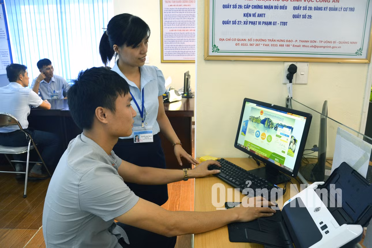 Cán bộ Trung tâm Hành chính công TP Uông Bí hướng dẫn người dân kê khai hồ sơ qua hệ thống website. Ảnh: Trúc Linh