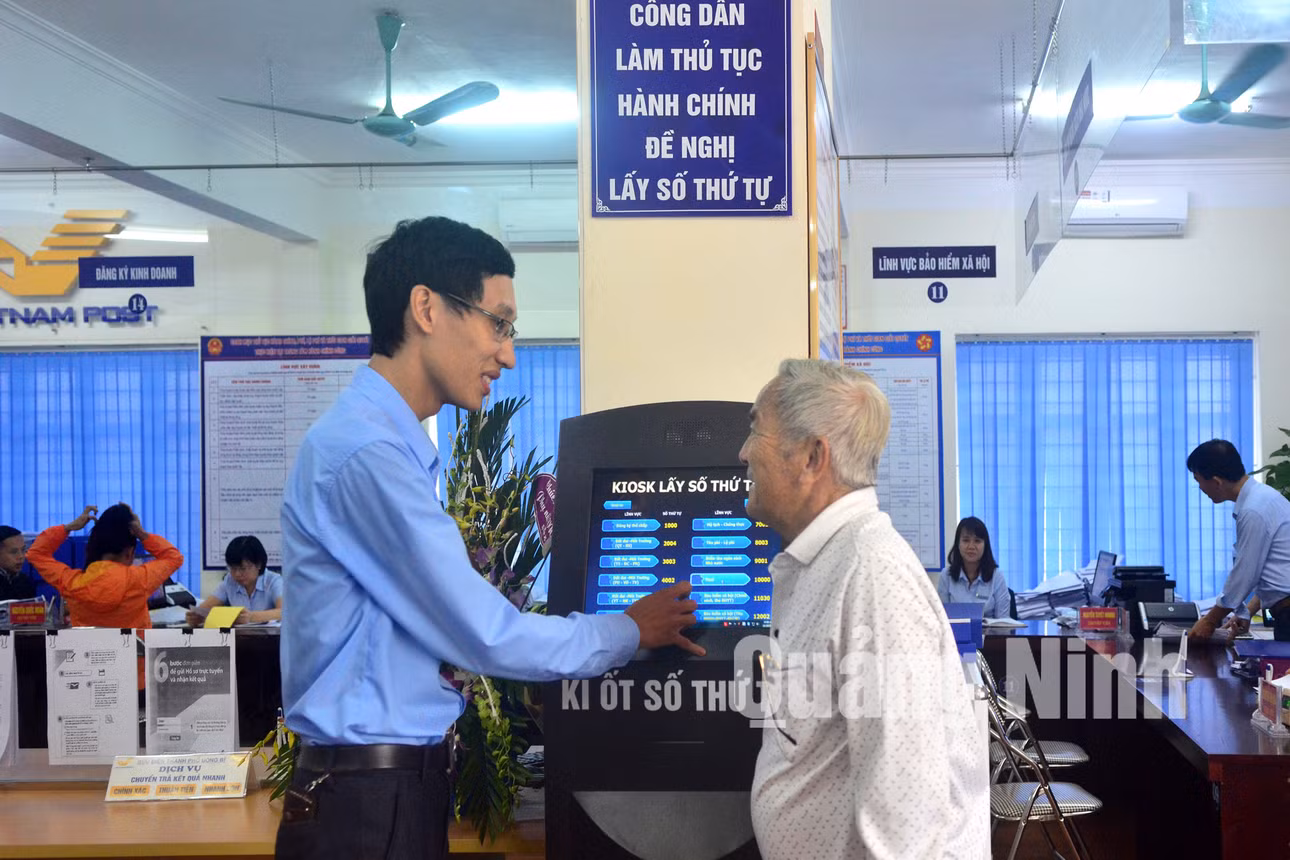 Hướng dẫn người dân lấy số thứ tự tại ki ốt để giải quyết thủ tục hành chính. Ảnh: Nguyễn Dung