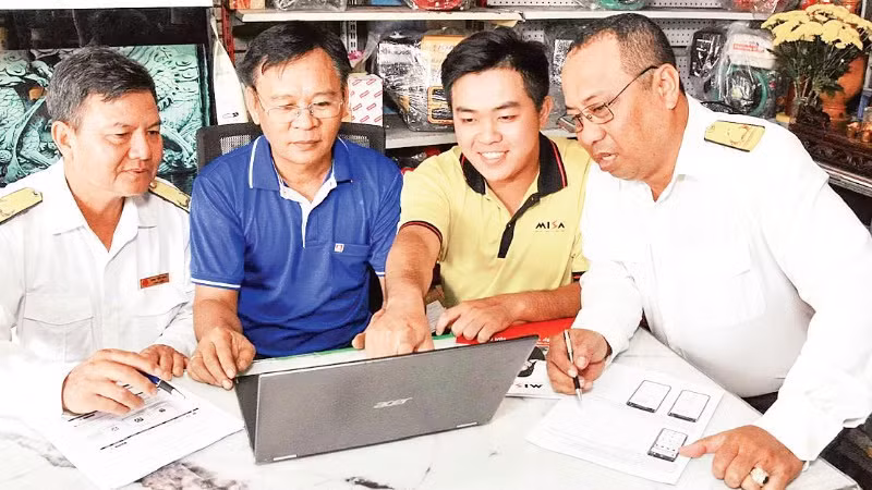 Công chức Thuế cơ sở 4 (An Giang) hướng dẫn chủ hộ kinh doanh cách kê khai hàng hóa. (Ảnh: KIỀU DIỄM)