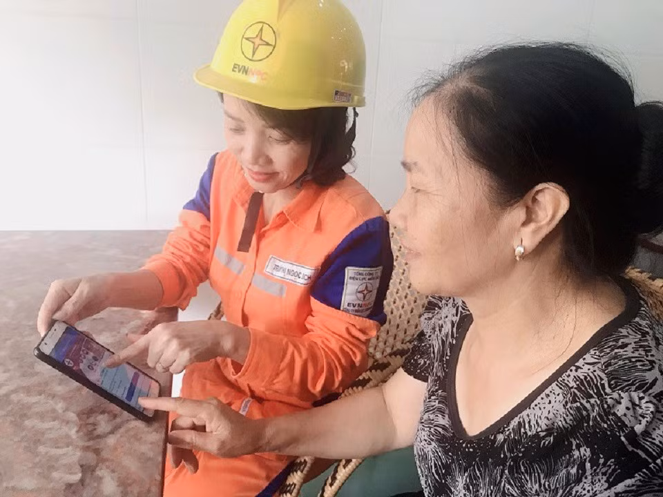 Nhân viên Công ty Điện lực Quảng Ninh hướng dẫn người dân cách thanh toán qua tài khoản ngân hàng. Ảnh: Hoàng Quỳnh
