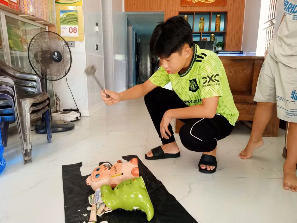 Hai anh em đập lợn đất ủng hộ các bạn học sinh vùng lũ.