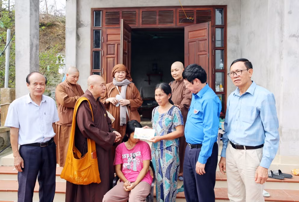Đại diện Chùa Quan Âm (Quận 12, TP Hồ Chí Minh) cùng các phật tử trao hỗ trợ 2 triệu đồng cho gia đình chị Nguyễn Thị Bảy, thôn Ngọc Nam, xã Ngọc Vừng, huyện Vân Đồn có nhà bị tốc mái do bão số 3. Ảnh: Minh Đức