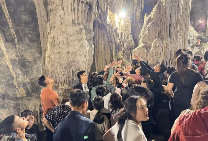 Du khách dừng lại ở lối ra trong động Hương Tích, chùa Hương, để hứng những giọt nước chảy ra từ khối nhũ đá với mong muốn may mắn cho năm mới. Ảnh: Ngọc Thành