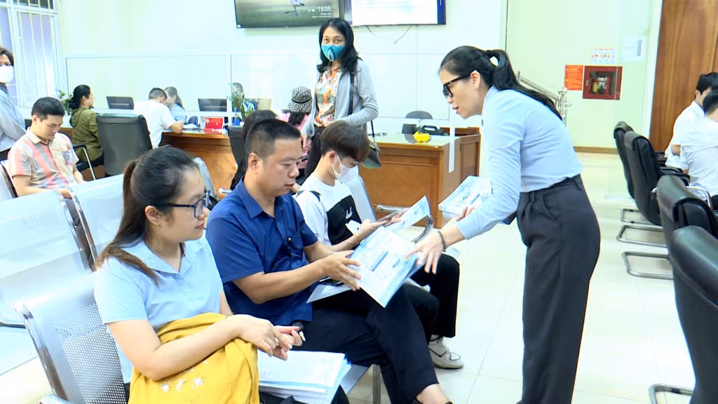 Cán bộ Trung tâm Hành chính TP Cẩm Phả phát tờ rơi hướng dẫn làm TTHC trực tuyến.