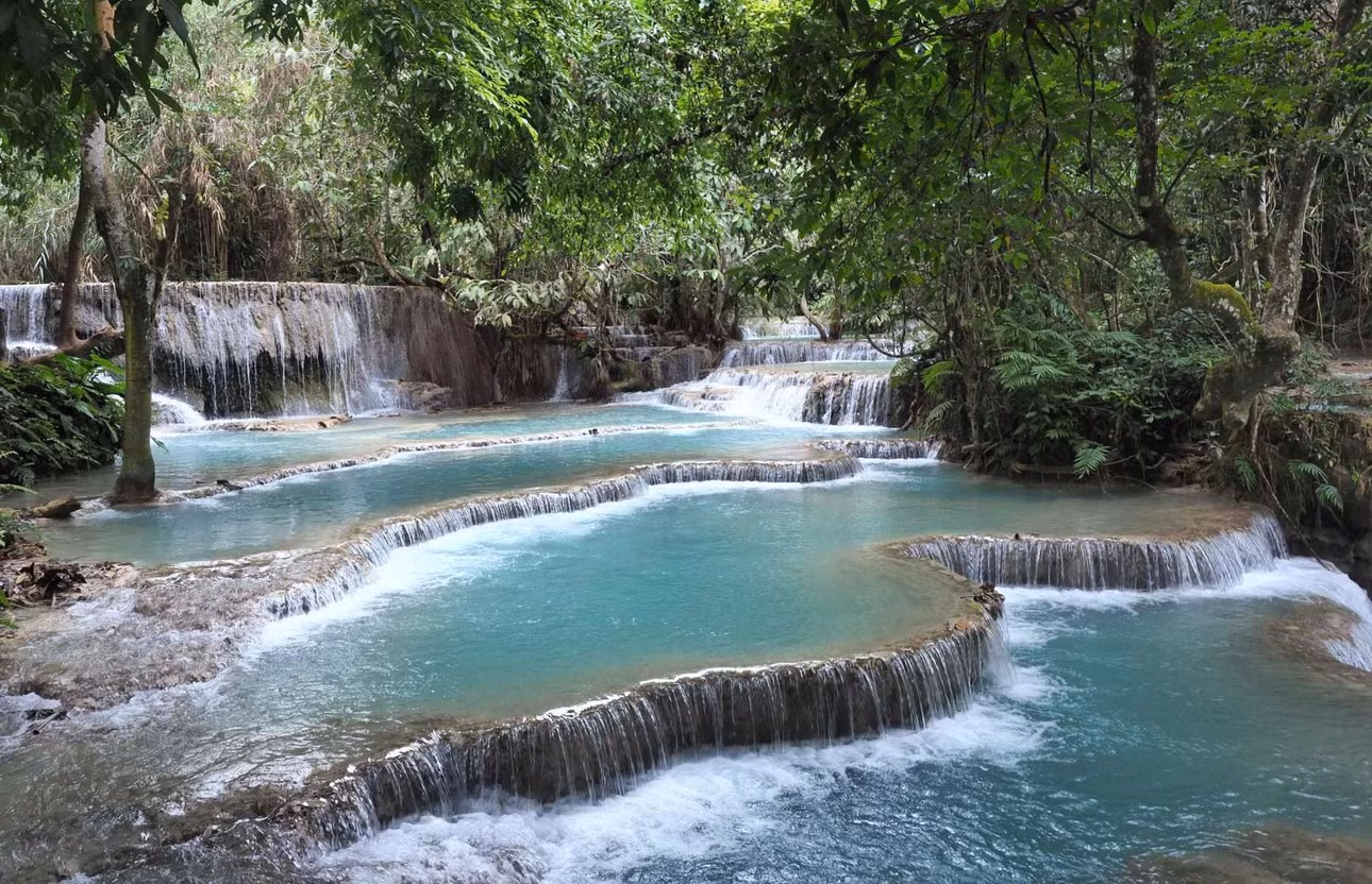 Thác Kuang Si hay Tat Kuang Si (Lào) cách trung tâm thành phố Luangprabang khoảng 30km về phía nam. Thác Kuang Si là quần thể gồm 3 ngọn thác, thác chính có độ cao lên đến 60m với dòng nước khổng lồ đổ xuống tạo nên khung cảnh trắng xóa hùng vĩ. Thác nước còn được bao bọc bởi núi rừng hùng vĩ tạo nên bức tranh nhiên nhiên tuyệt đẹp.