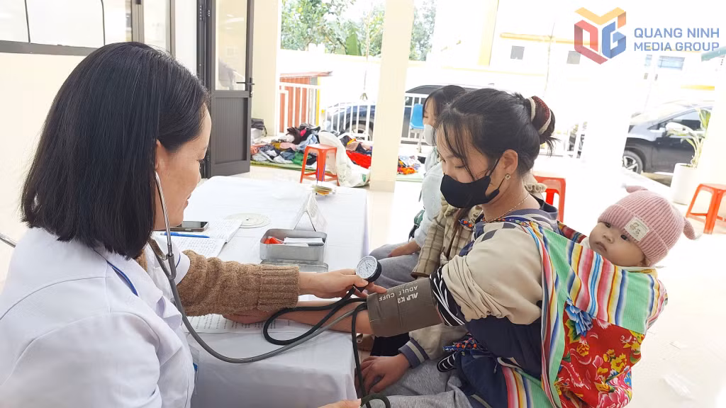 Cán bộ y tế khám sức khỏe cho một bà mẹ trẻ người Dao.