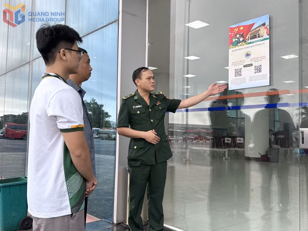 Cán bộ Đồn BPCKQT Móng Cái hướng dẫn cư dân biên giới cách quét mã QR tìm hiểu quy định của pháp luật về hoạt động xuất nhập cảnh. 