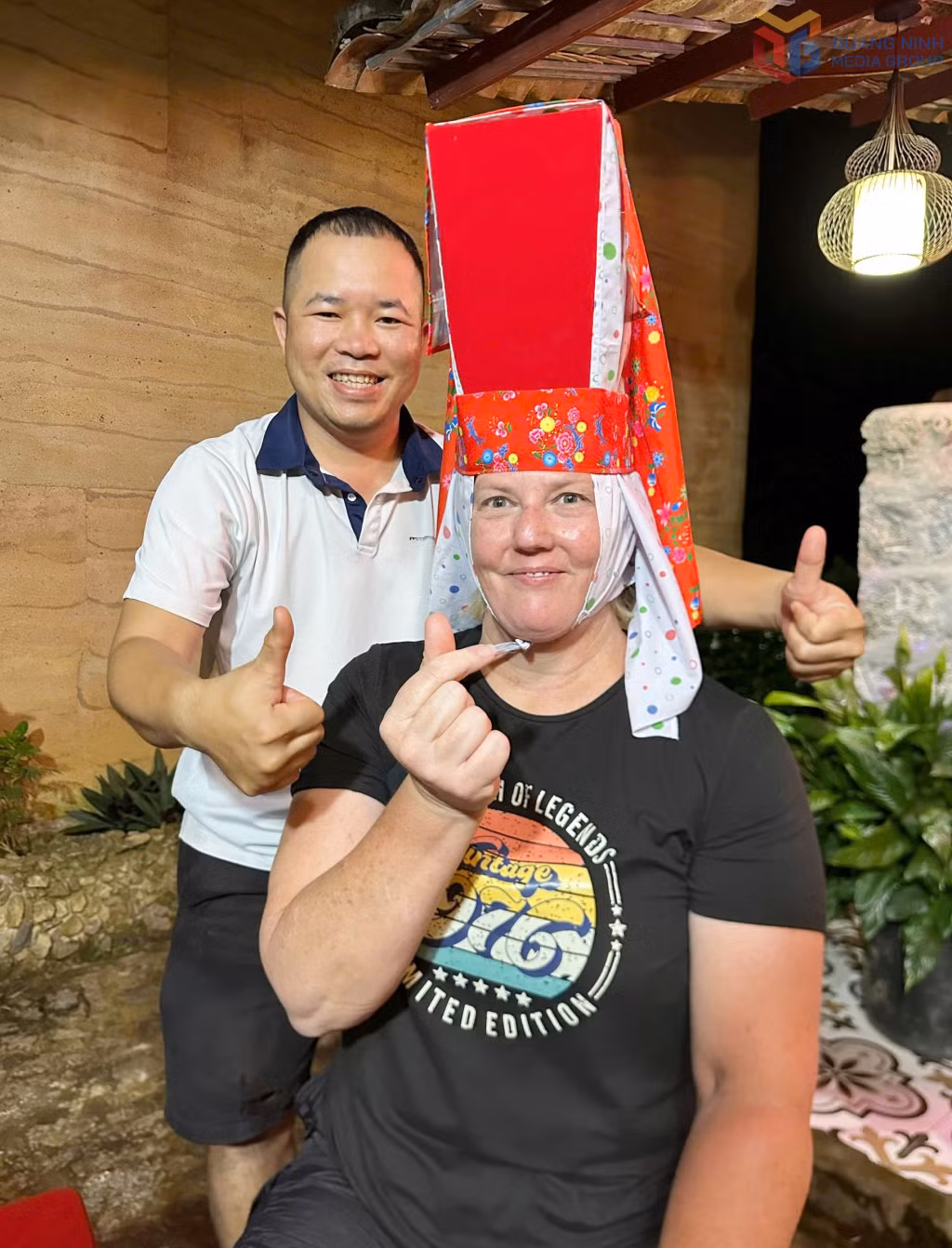 Chị Kristy Shooter (du khách đến từ Australia) thử trải nghiệm đội mũ phụ nữ người Dao Thanh Phán trong chuyến du lịch tại các xã Bình Liêu, Lục Hồn và Hoành Mô tháng 7/2026.