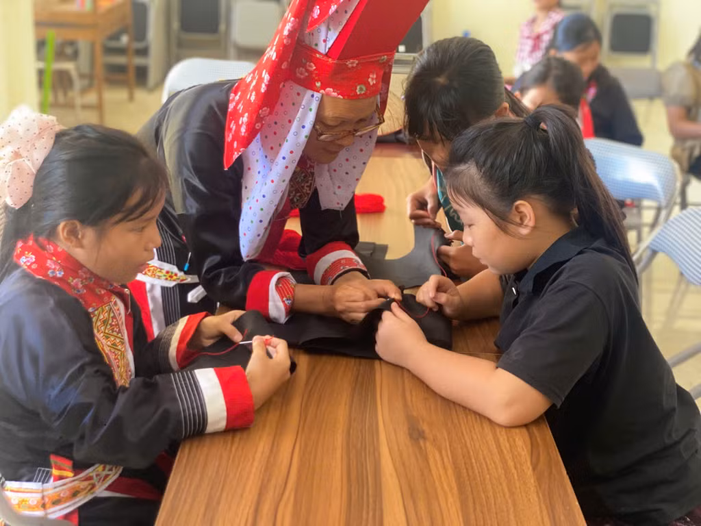 Nghệ nhân hướng dẫn các em từng đường kim, mũi chỉ trong nghề thêu truyền thống.