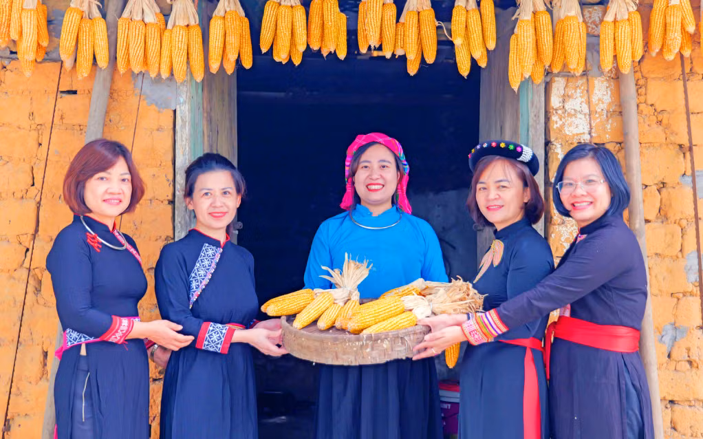 Du khách thích thú diện trang phục, check-in trước căn nhà đất của người Tày (3-2026). Ảnh: Tạ Quân