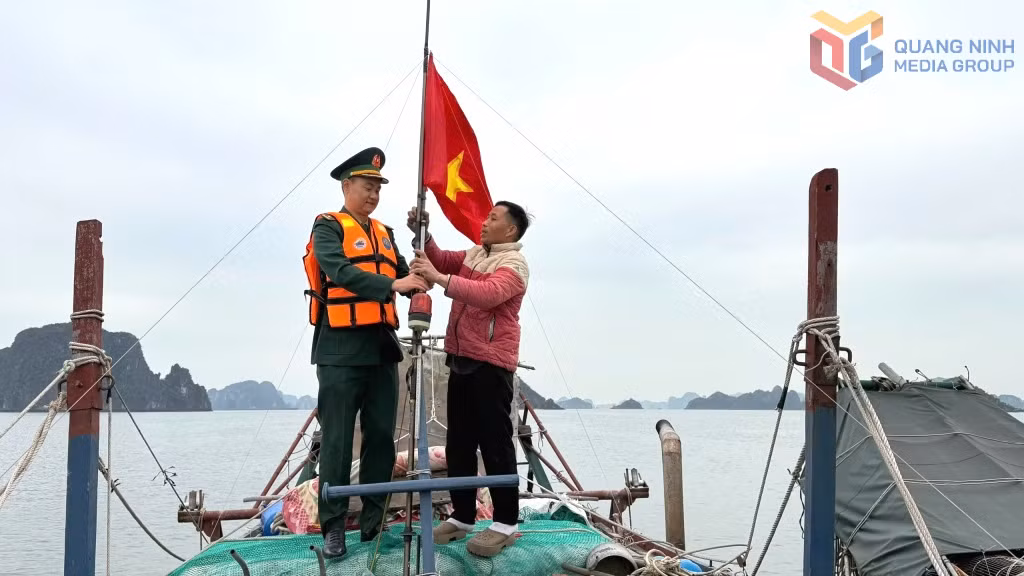 Cán bộ Hải đội Biên phòng 2 giúp ngư dân treo cờ Tổ quốc.
