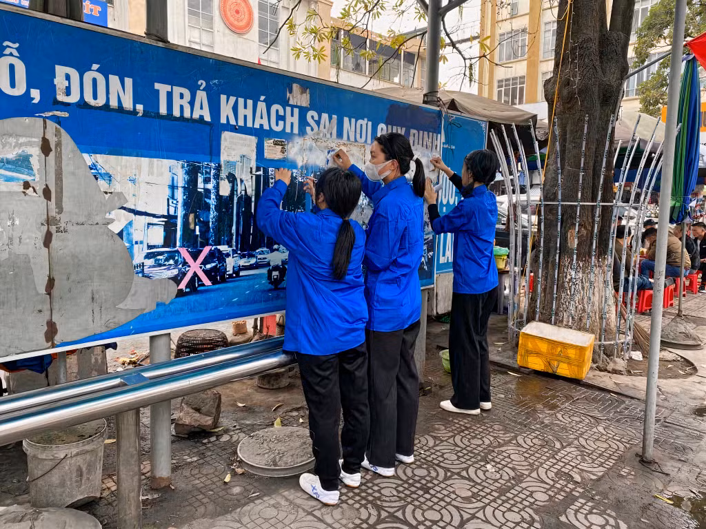 Thanh niên Cẩm Phả tham gia bóc xóa những biển quảng cáo sai quy định.