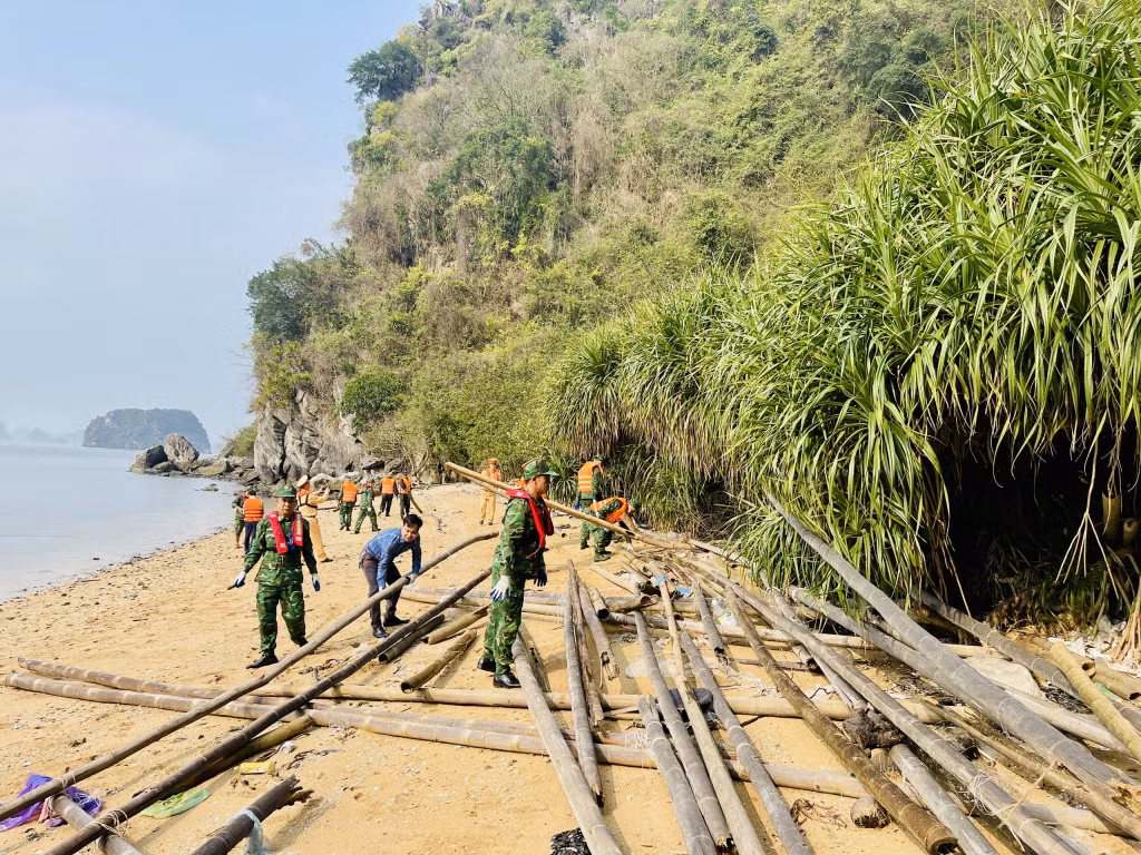 Các lực lượng chức năng thu gom bè mảng trôi dạt vào các khe, chân núi đá ở khu vực hòn Cặp Liền.