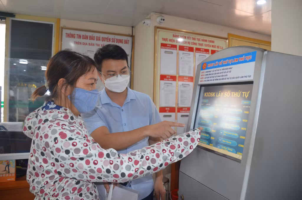 Cán bộ Trung tâm Hành chính công TX Quảng Yên hướng dẫn người dân lấy số thứ tự tại kios thông tin.