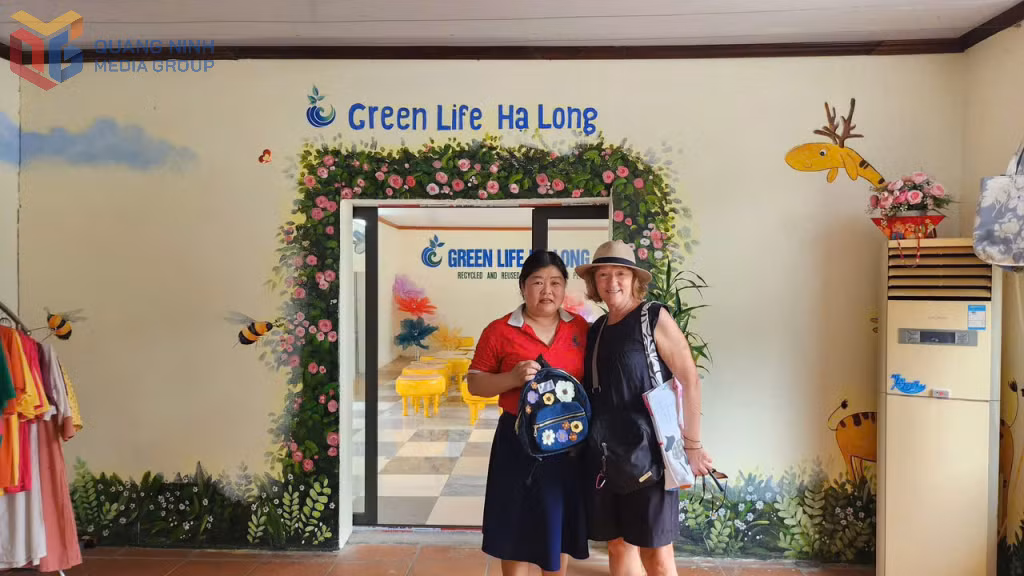 Chị Trần Thị Hương, Giám đốc HTX Green Life Hạ Long và khách du lịch chụp ảnh cùng sản phẩm túi tái chế.