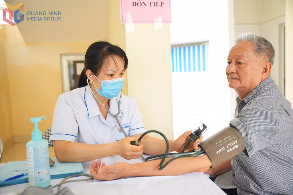 Điều dưỡng Bệnh viện Sản Nhi Quảng Ninh đo huyết áp cho người dân đến khám trong chương trình khám bệnh lưu động tại xã Vũ Oai (TP Hạ Long).