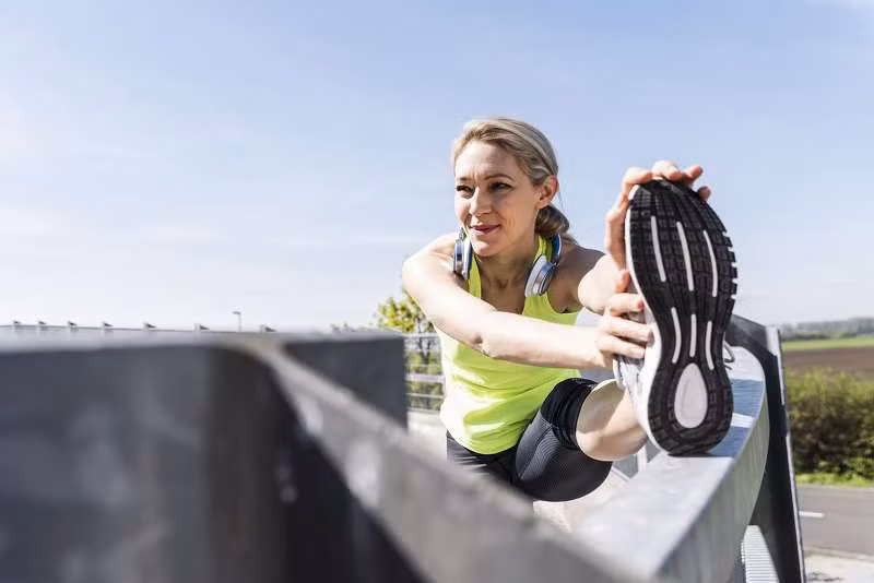 Người phụ nữ đang duỗi người trước khi chạy ra ngoài trong thời tiết đẹp