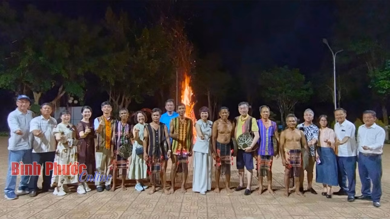 Du khách chụp hình lưu niệm cùng các nghệ nhân trình diễn chiêng tại Khu bảo tồn văn hóa dân tộc S’tiêng sóc Bom Bo