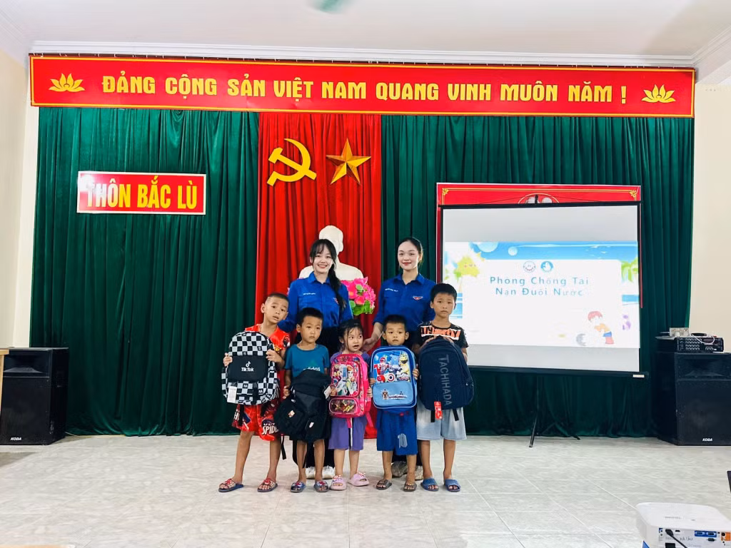 Bàn Thị Mỹ Duyên cùng đại diện đoàn tình nguyện của Trường Đại học Công nghiệp Quảng Ninh tặng quà cho trẻ em có hoàn cảnh khó khăn ở xã Hà Lâu, huyện Tiên Yên. Ảnh: Nhân vật cung cấp.
