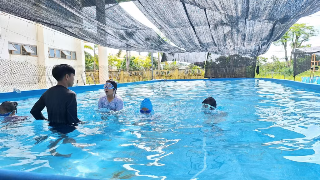 Thầy giáo hướng dẫn các em tư thế cơ bản trong khi bơi.