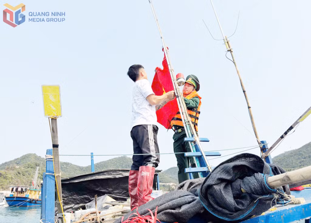 Cán bộ Đồn Biên phòng Đảo Trần giúp ngư dân treo cờ Tổ quốc.