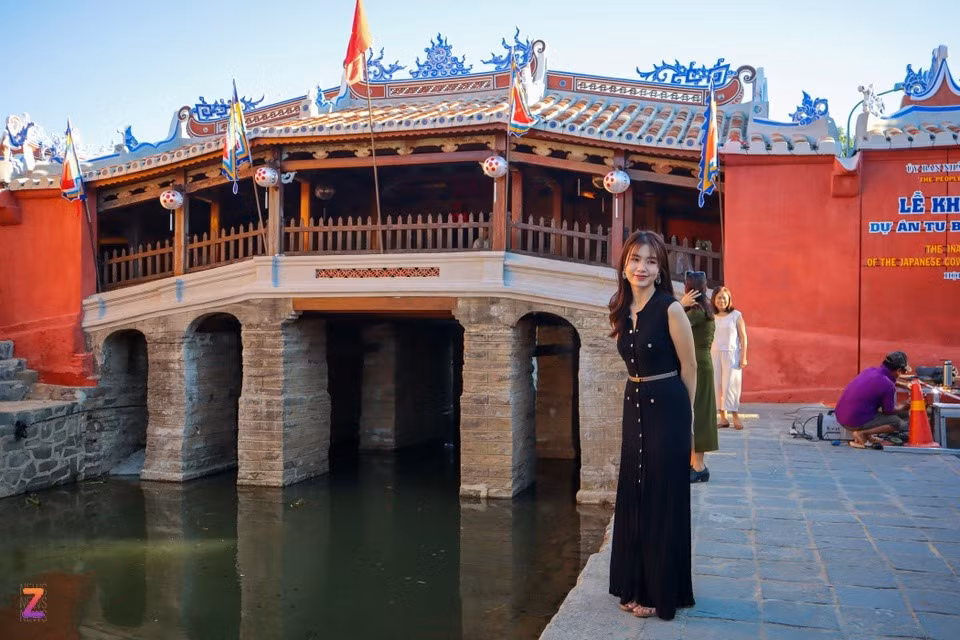 Du khách chụp ảnh trước Chùa Cầu sau khi công trình hoàn tất trùng tu hồi cuối tháng 7. Ảnh: Phạm Toàn.
