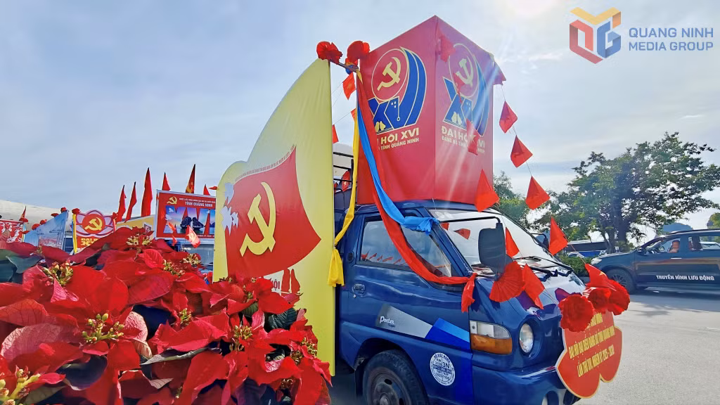 Xe cổ động dẫn đầu đoàn trang trí biểu trưng Đại hội, tranh cổ động, khẩu hiệu, hoa dây, cờ Đảng, cờ Tổ quốc.