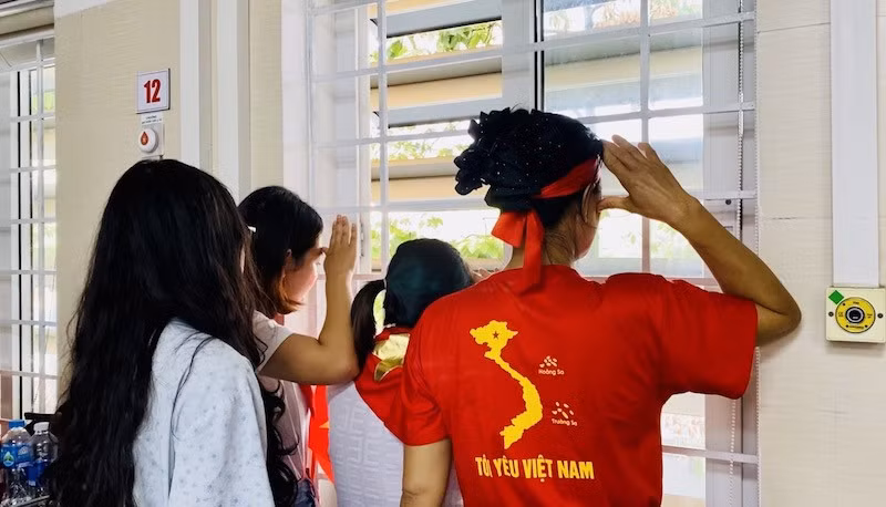 Chào cờ, hát quốc ca qua ô cửa sổ. Ảnh: Thùy Linh